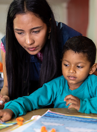 Female tutor helping a young boy with an educational project